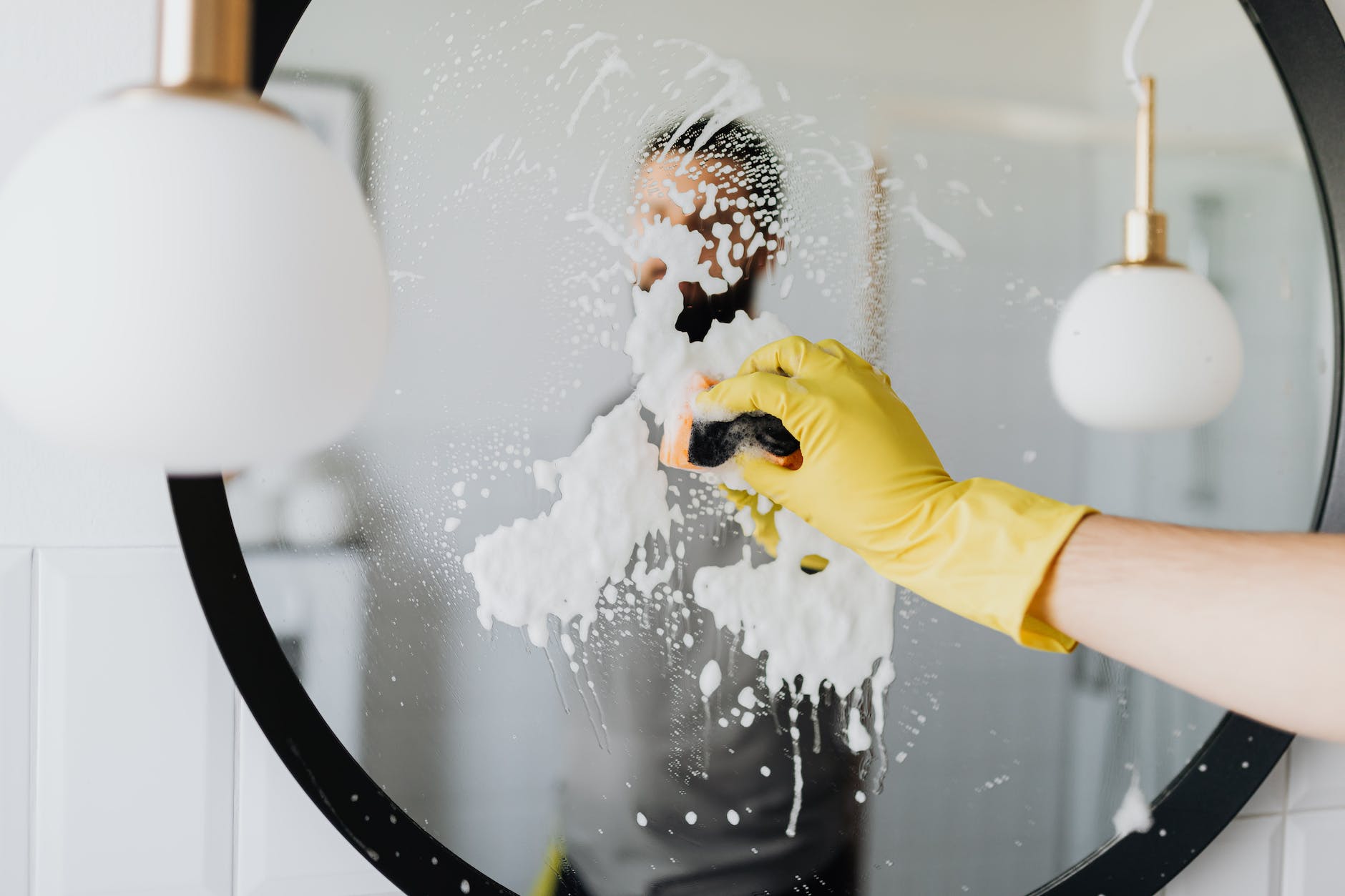 faceless man wiping mirror in bathroom